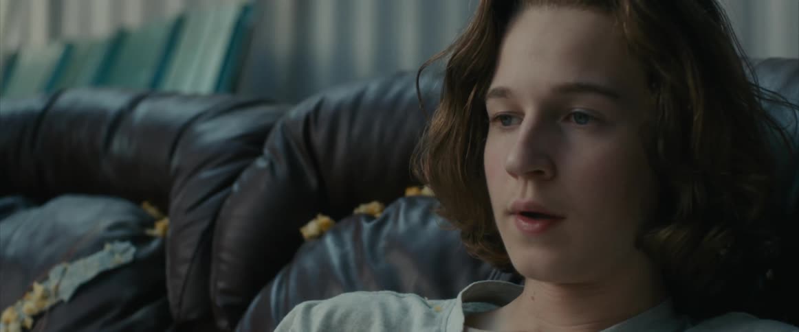 A teenager sighs while sitting on the couch