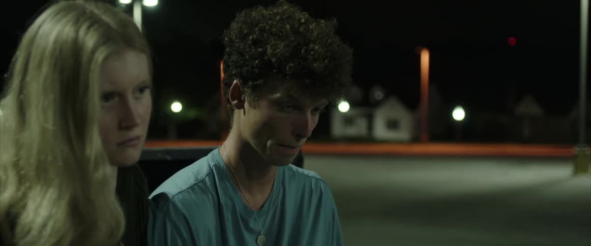 Two teenagers sit on truck bed in empty parking lot