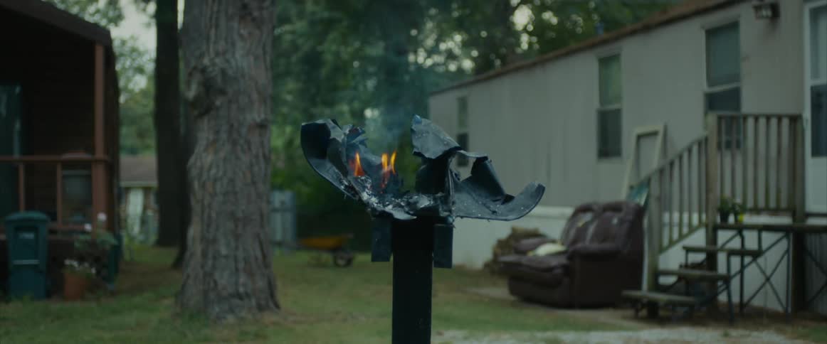 A mailbox at a trailer park has been blown off its post and there are still flames burning on what is left of it