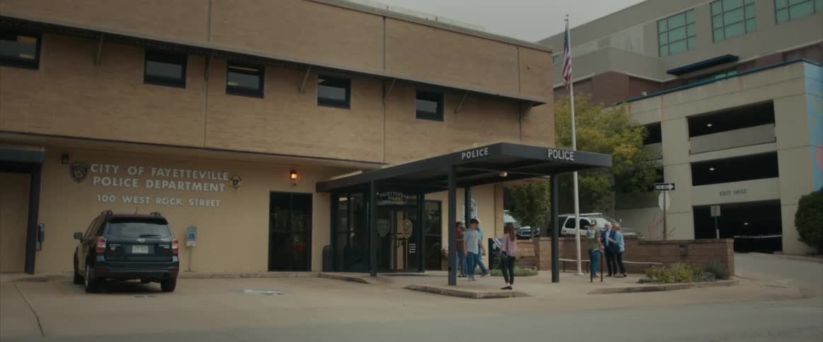 A group of people walk out of a police department building