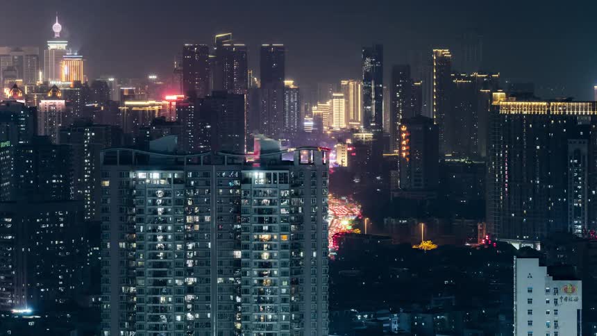 Traffic passes through a dense city lit up with neon lights at night