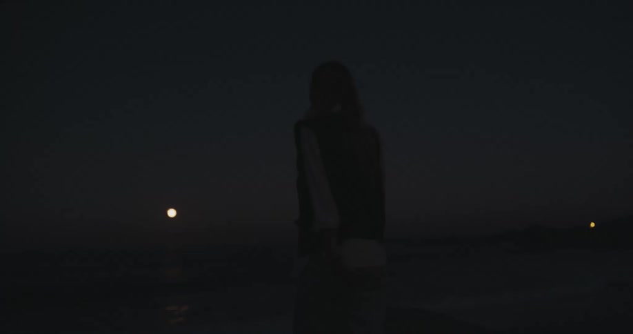 A woman walks on the beach at night