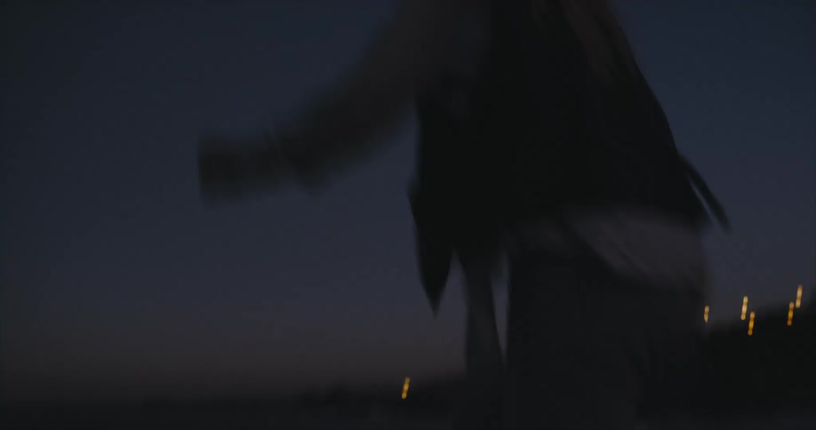 A person walking toward the beach jumps over a crevice in the rocks