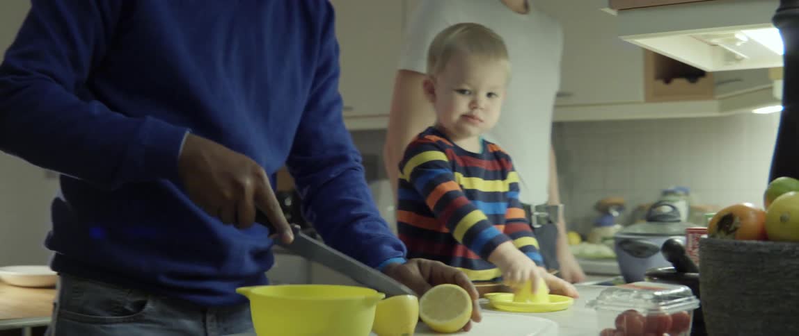 Child and Two Men Preparing Food Together in a Kitchen With Warm Family Interaction.