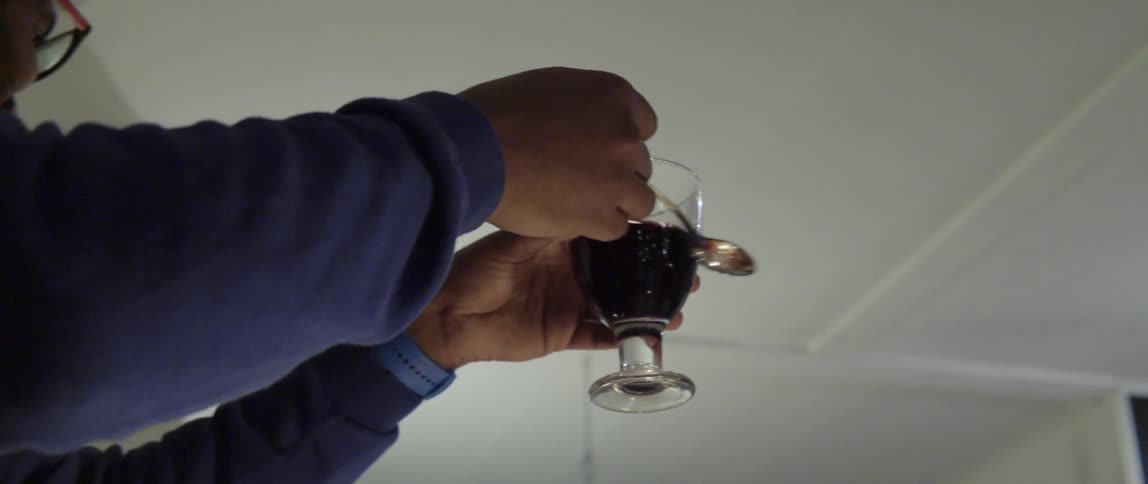 Man Taps a Glass With a Spoon to Make a Toast in a Warm Gathering.