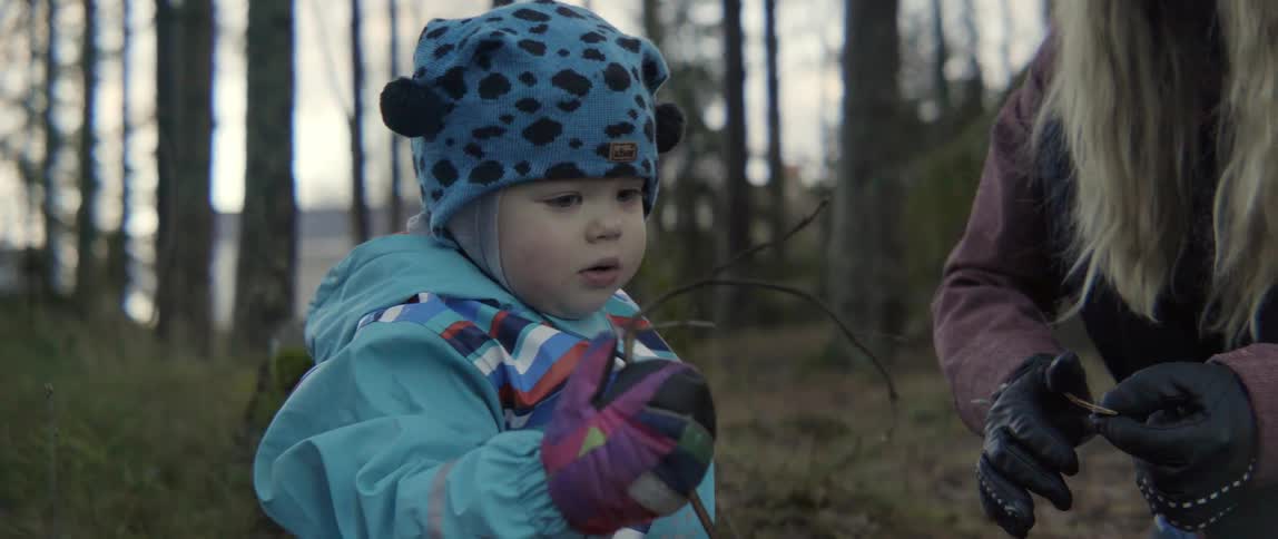 young boy in a blue leapord print exploring the woods during a cold winter day.
