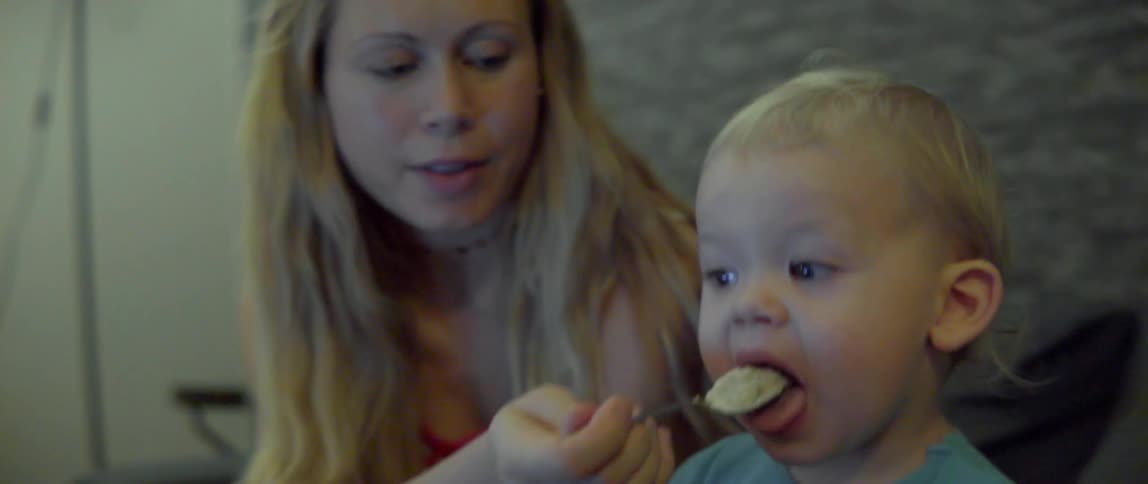 Heartwarming domestic scene of a mother providing a meal to her toddler in kitchen