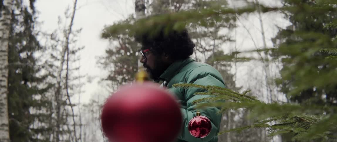 Man holding ornament near outdoor tree with warm joyful holiday spirit