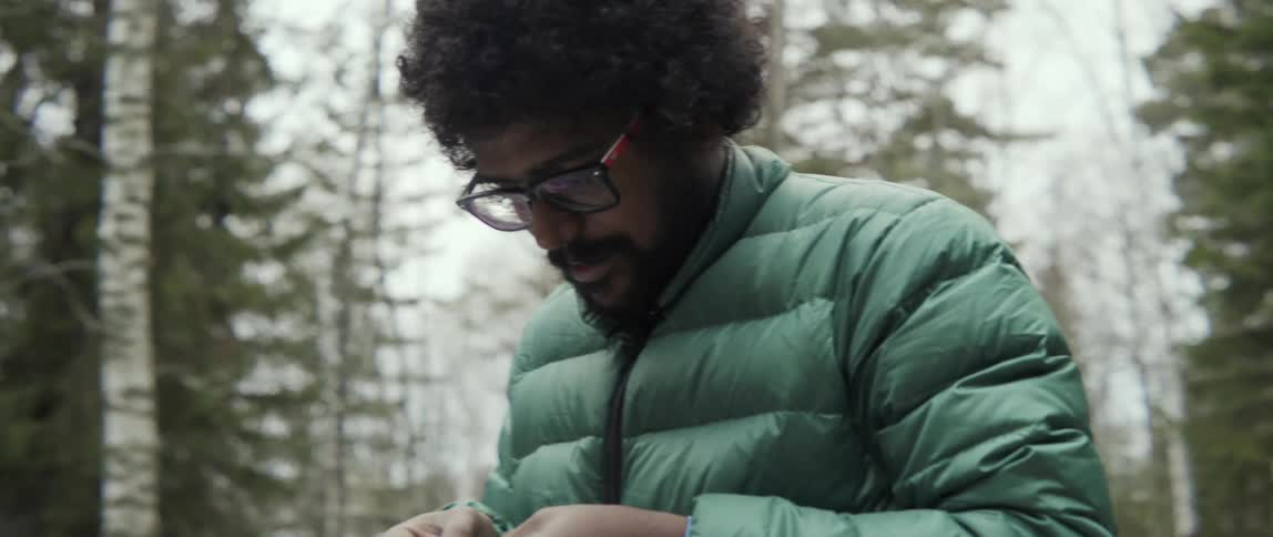 A man threads a string onto the loop on a tree ornament