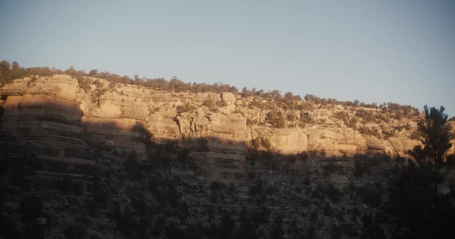 Shadows cover lower half of cliff under a blue sky