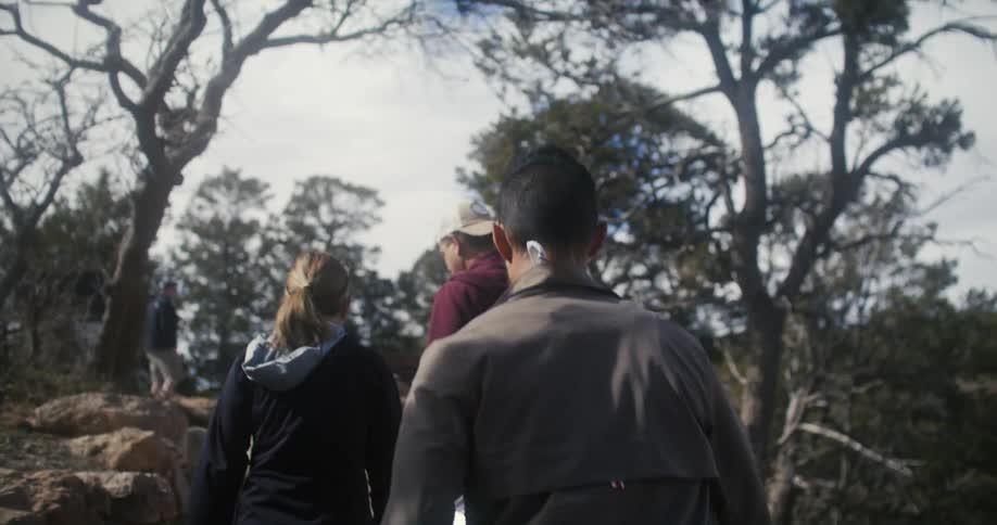 People talk while walking along trail under a cloudy sky