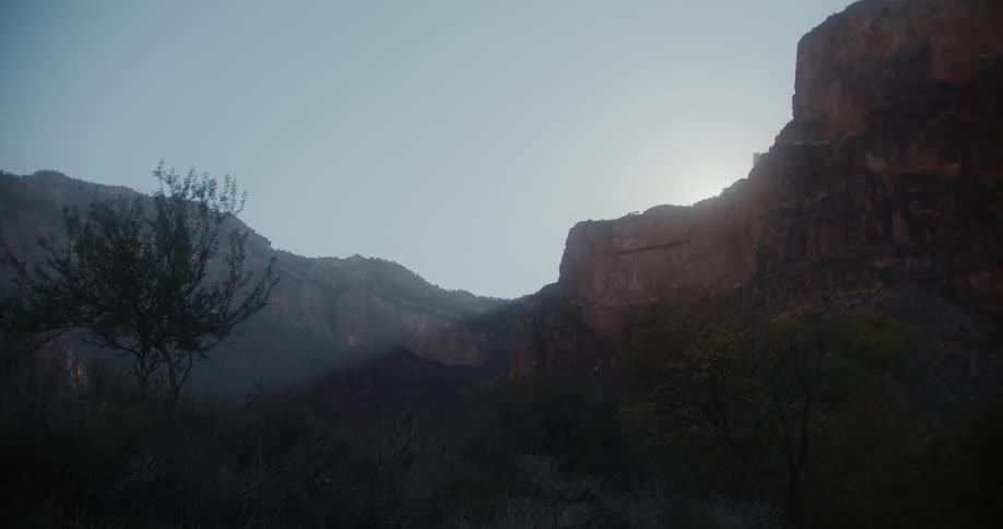 The sun shining over the ridge of a canyon