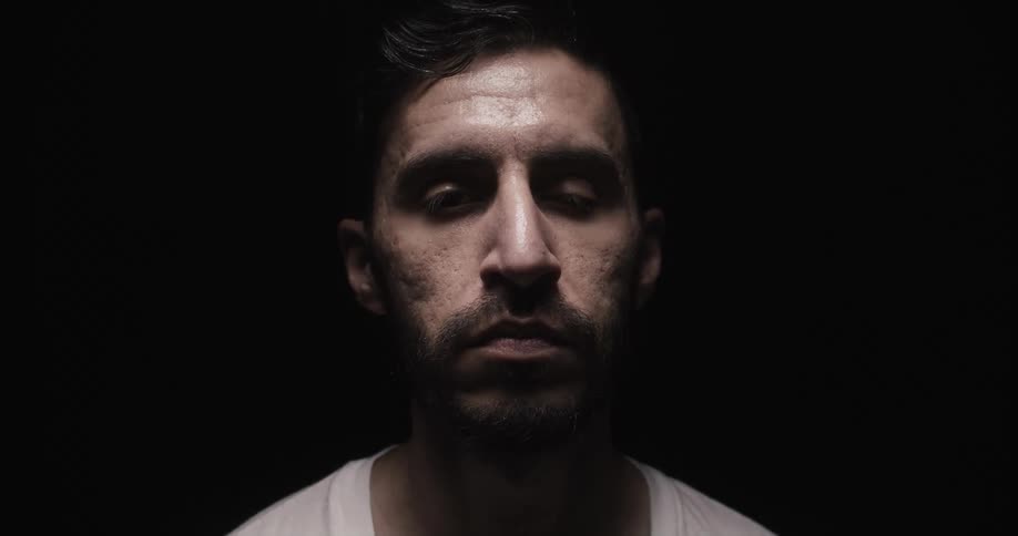 Man with beard faces the camera with eye contact in studio