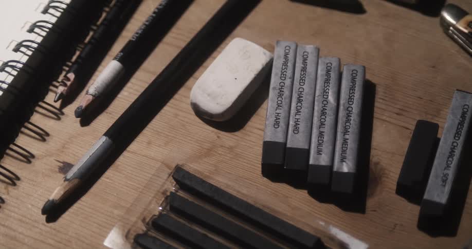 Sketch art supplies lay on a wooden table