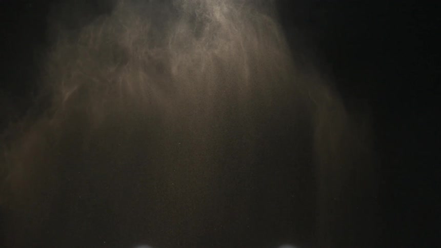 Thrown dust spreads against dark background