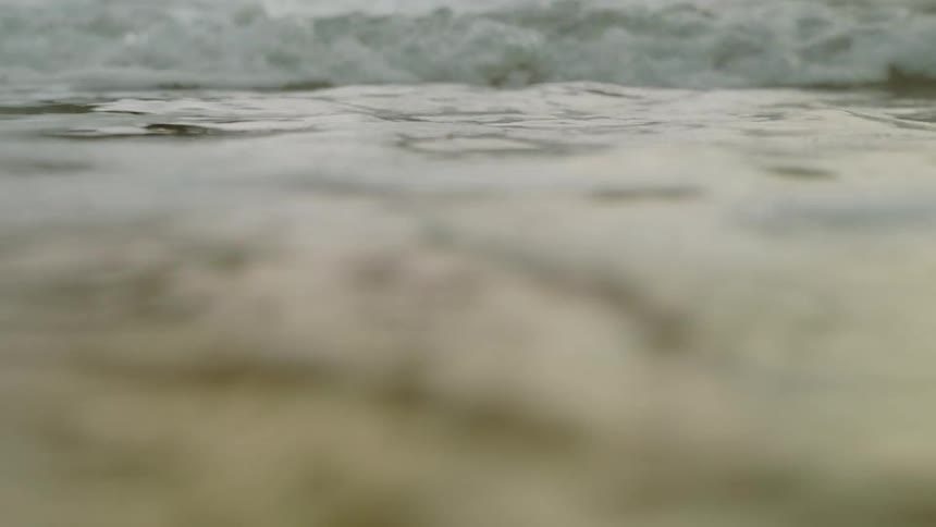 Waves roll in over wet sand on the beach