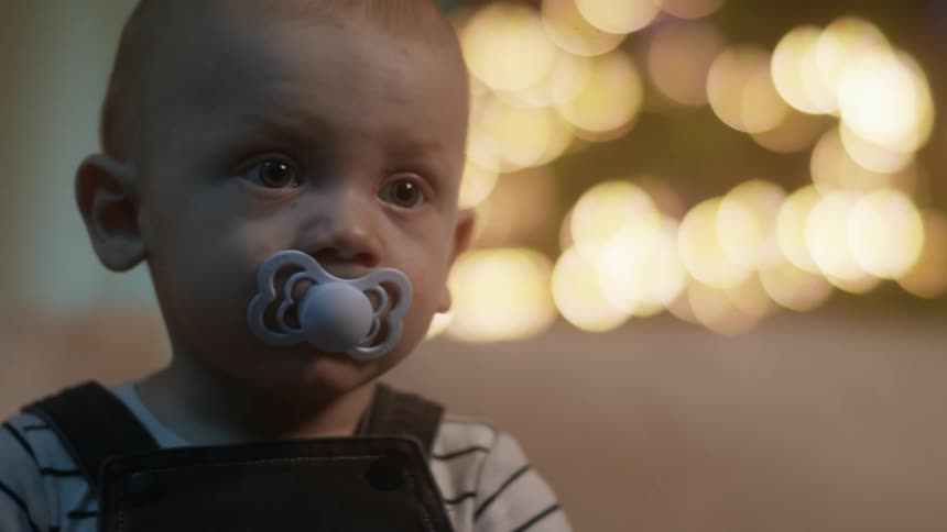 A baby boy sucks on a soother