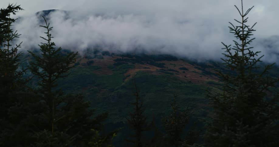 Clouds obscure the slope of a mountain during the day