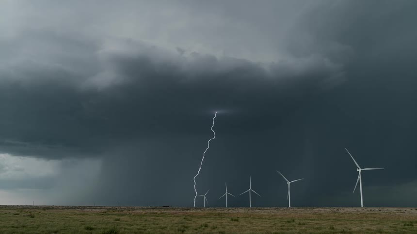 Wind turbines spin as lightning comes down from storm clouds