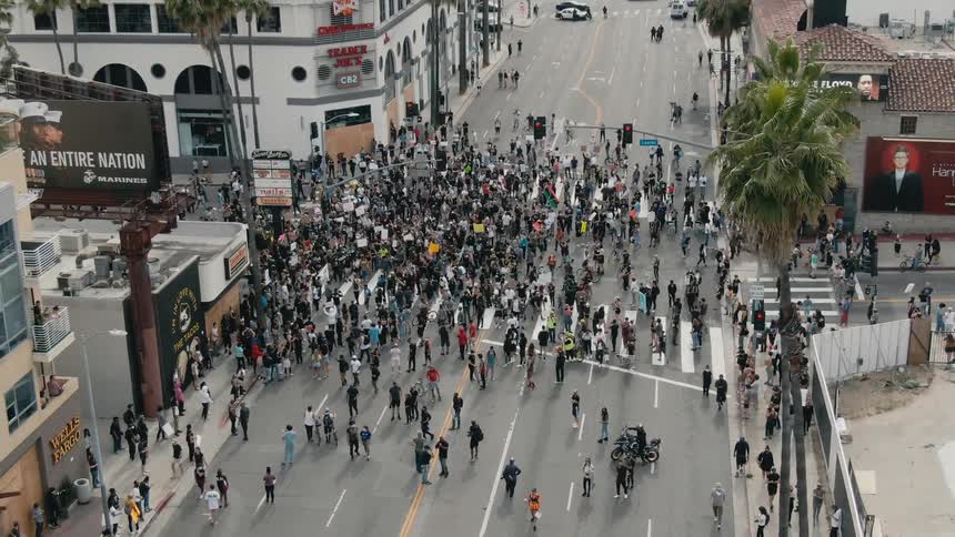 A large group of protesters occupy an intersection in a city during the day