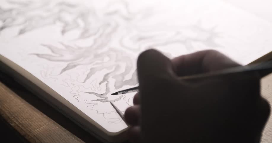 A man uses a paintbrush to sketch some artwork