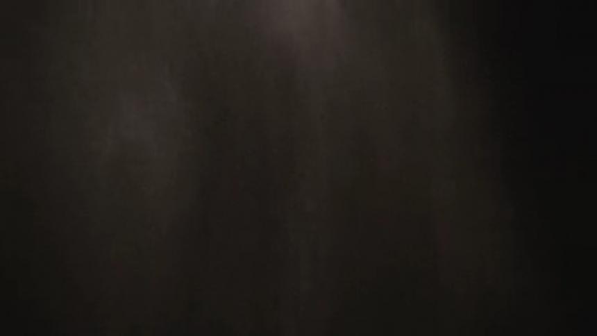 Pale particles fall and dissipate against a black background