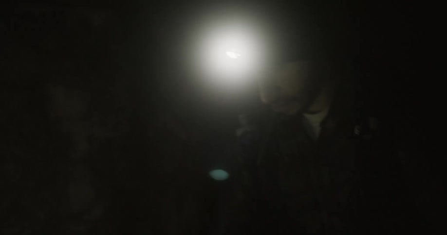 Man wearing a head lamp walking in a dark area