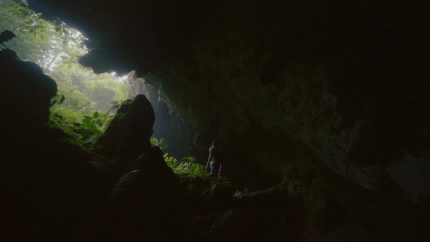 A man looks around at his surroundings while standing inside a cavern during the day