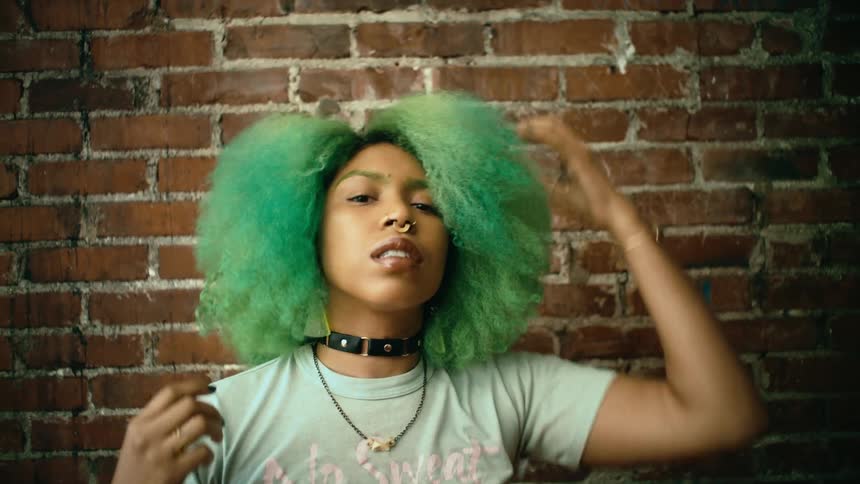 A young woman adjusts her hair with her hands while looking into the camera