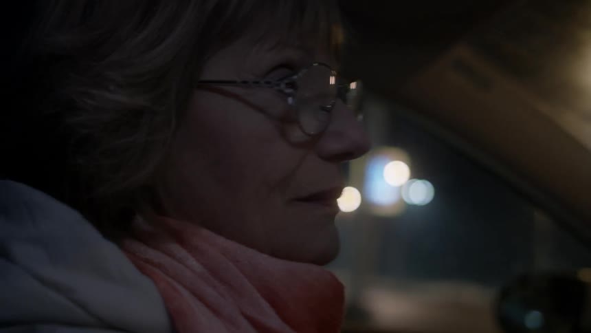 A woman drives a car through a city at night