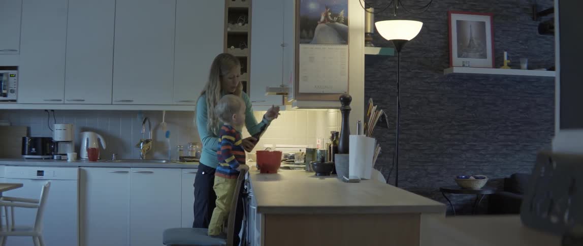 Young mother and small boy preparing food together in a bright contemporary domestic kitchen.