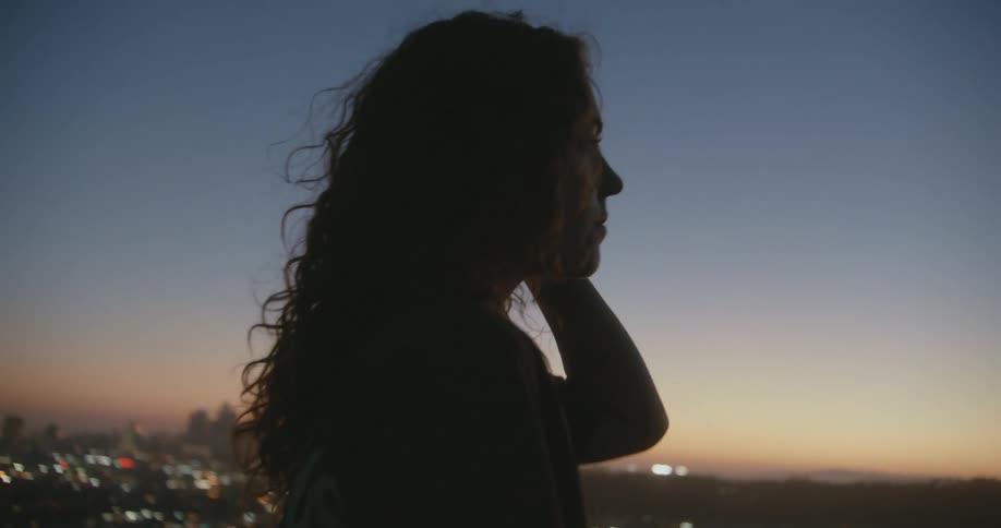 A teenage girl walks outside with the city skyline below her