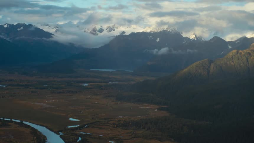 Thick cloud cover hangs over mountains and a valley with a river