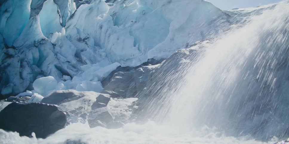 Water rushing down the rocky side of an ice and snow covered mountain