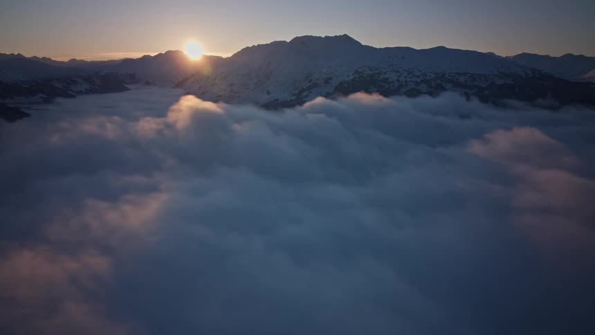 Time lapse of clouds rolling over a mountain range as the sun sets