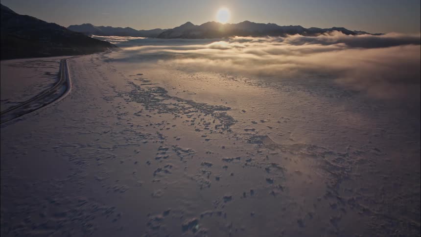 Low clouds sweep over a vast countryside covered in a snow during the day