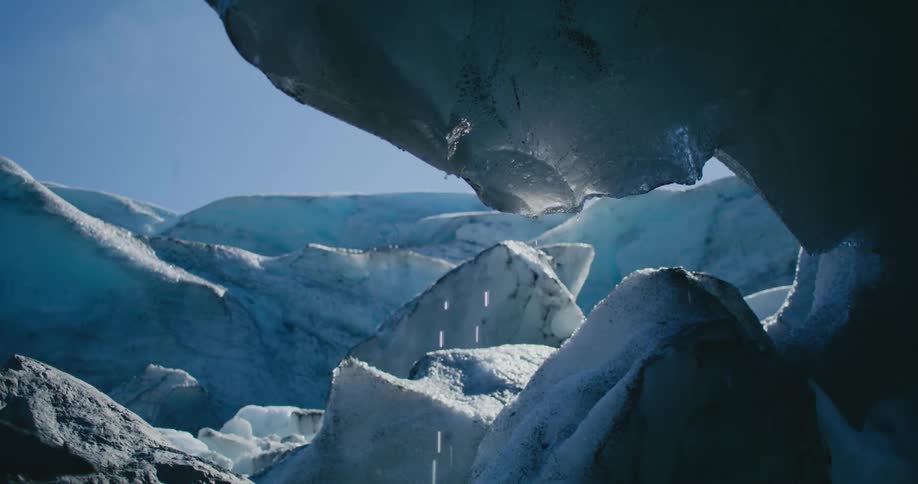 The sun is shining on arctic ice and it drips as it melts