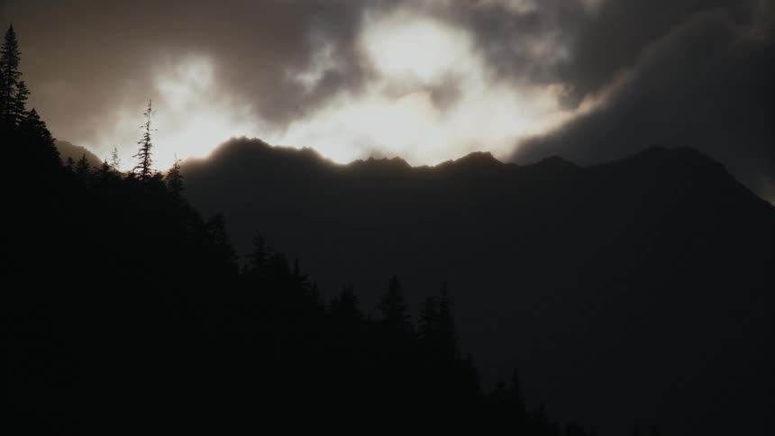 Clouds float over a dark mountain during the day