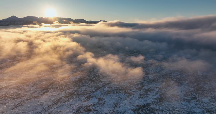 The sun shining over a cloudy landscape at sunrise