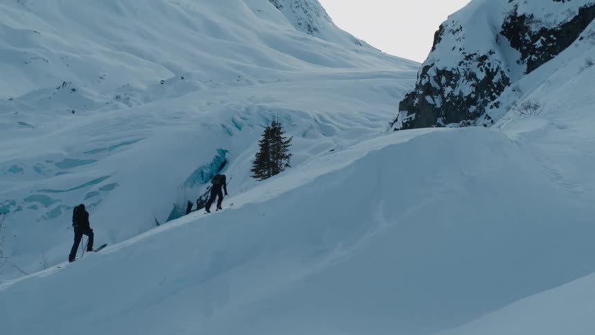 Two skiers trekking a snow covered ridge uphill