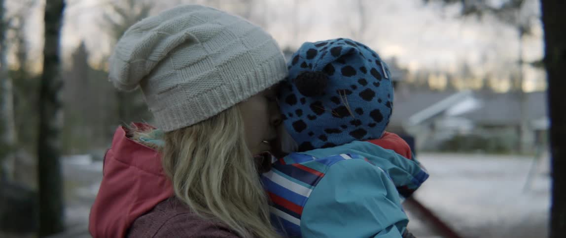 a woman comforting her small boy while outdoors in a forest.