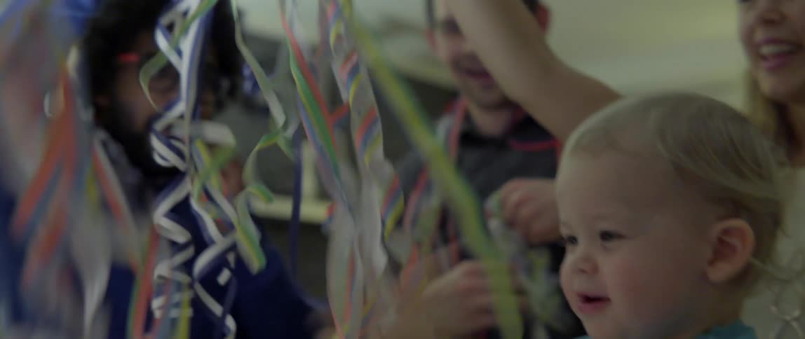 Heartwarming domestic scene of a young child playing with colorful ribbons at a party.