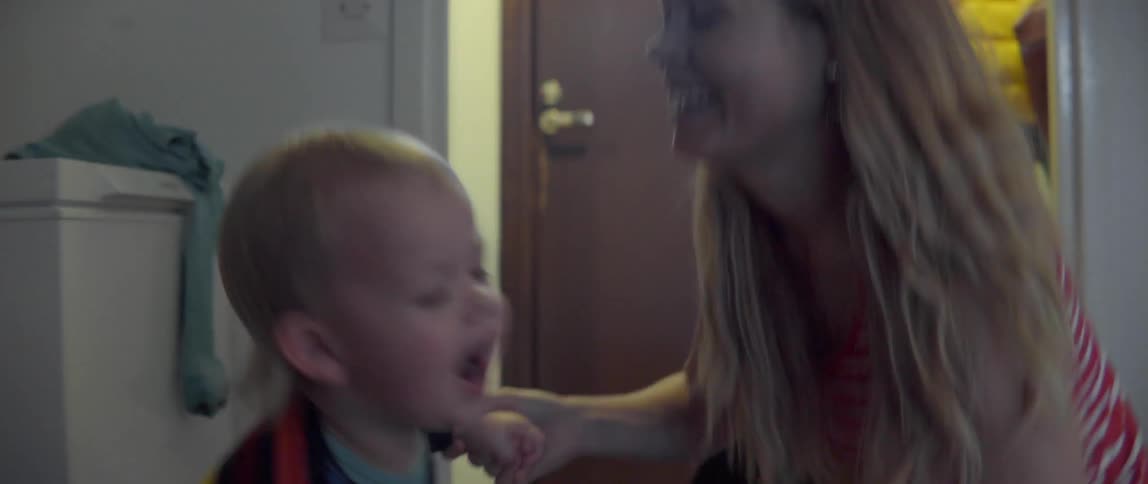 A laughing toddler and woman enjoying a heartwarming interaction at home.