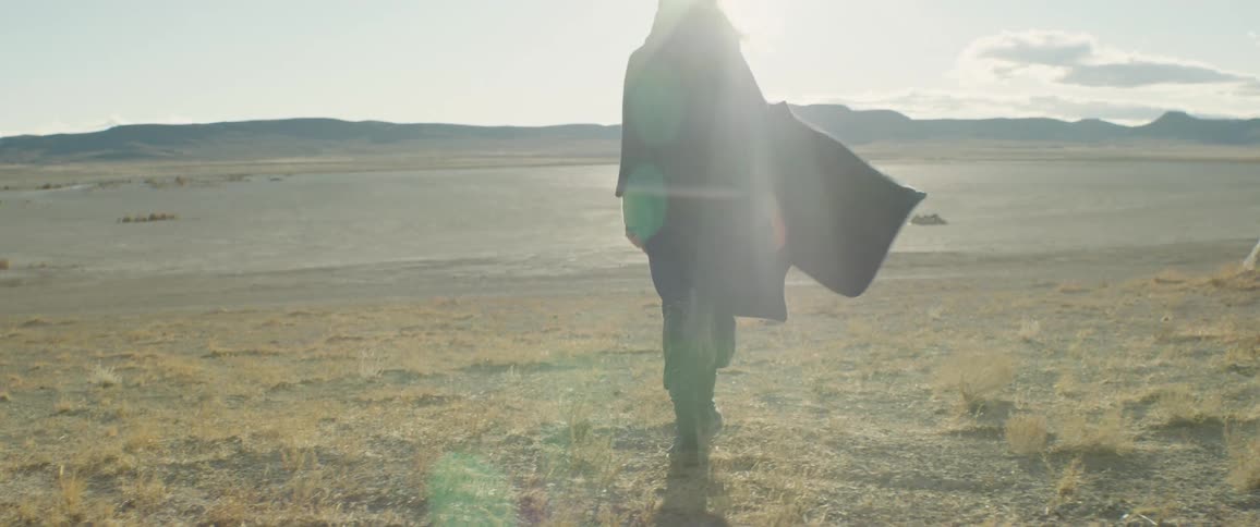 A woman walks through a field toward a lake