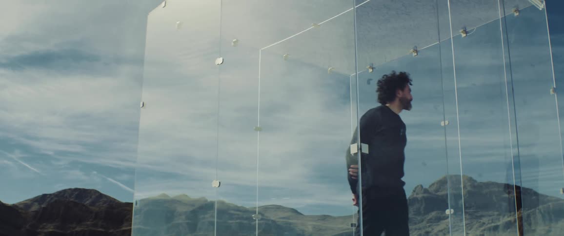 A man paces inside a clear cube in a canyon