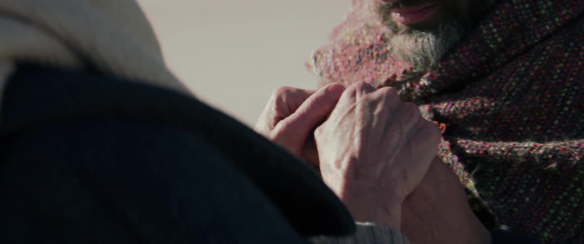 A man nervously looks up at the woman holding his hands clasped in hers