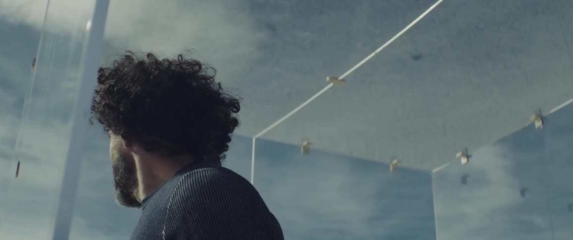 A man stands and looks out a glass door