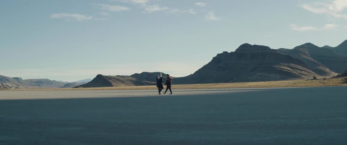 Two people are walking in the desert