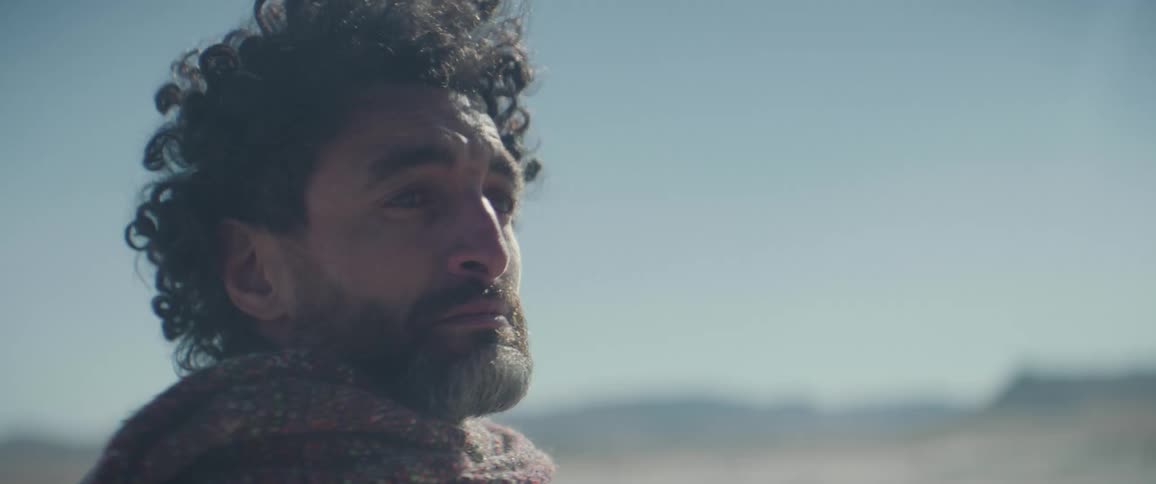 A worried man looks around as the wind carries sand in the air