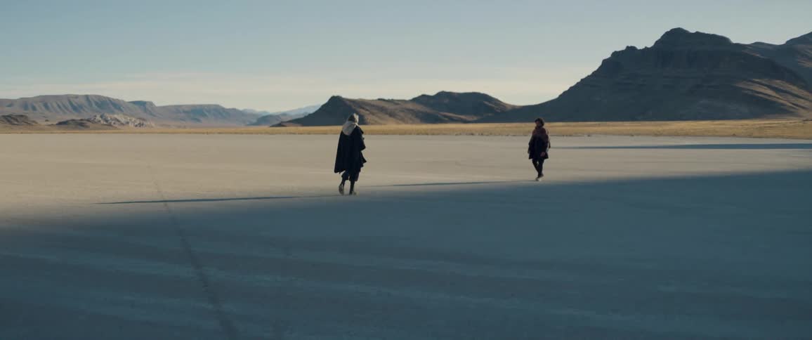 Mother and son slowly walking towards each other in the middle of a plain area outdoors at a sunny day